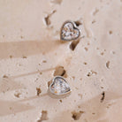 Heart-shaped earrings on a textured beige surface