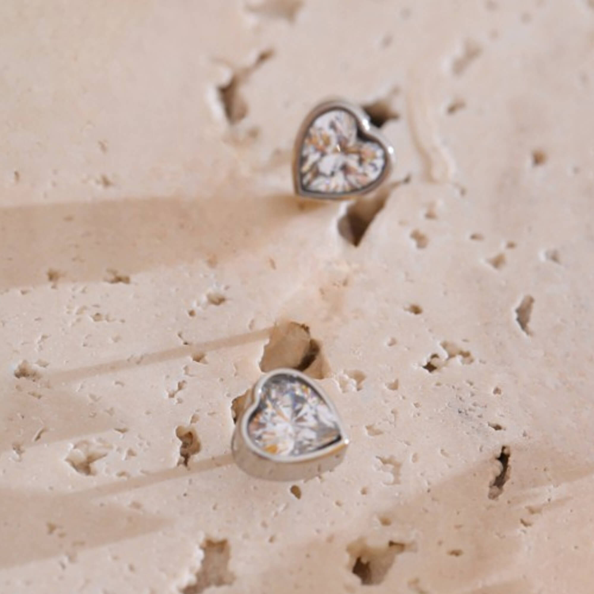 Heart-shaped earrings on a textured beige surface